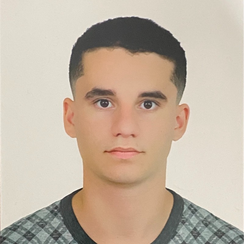 Hassan Ouadghiri smiling and facing the camera in a well-lit indoor setting with a neutral background, conveying a friendly and approachable mood